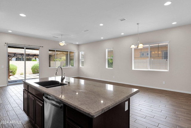 kitchen featuring sink, decorative light fixtures, dishwasher, and a center island with sink