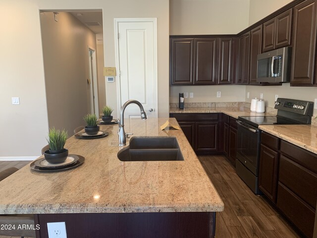 kitchen with black appliances, sink, light stone countertops, dark brown cabinetry, and light hardwood / wood-style flooring