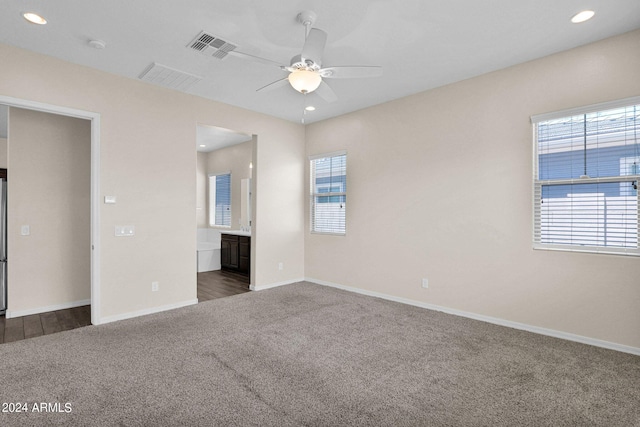 unfurnished bedroom with ensuite bath, dark colored carpet, and ceiling fan