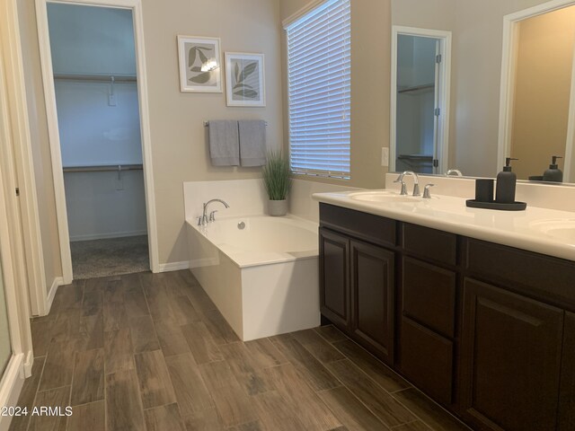 bathroom with hardwood / wood-style flooring, dual bowl vanity, and separate shower and tub