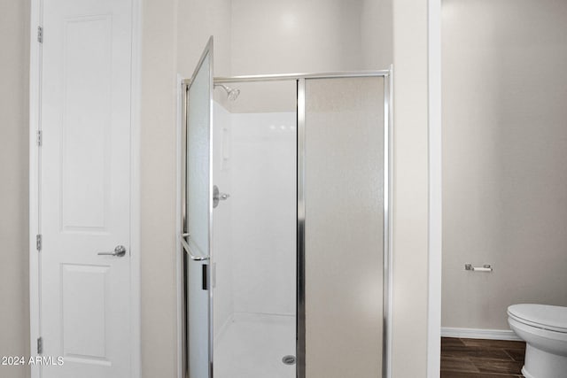 bathroom with an enclosed shower, wood-type flooring, and toilet