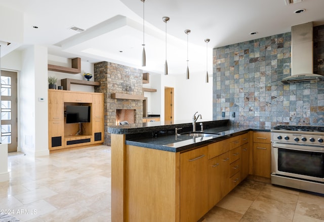 kitchen featuring high end range, kitchen peninsula, wall chimney exhaust hood, and sink