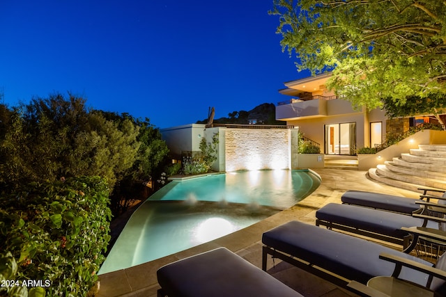 pool at night featuring a patio