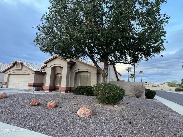 view of front facade featuring stucco siding, an attached garage, driveway, and a tiled roof