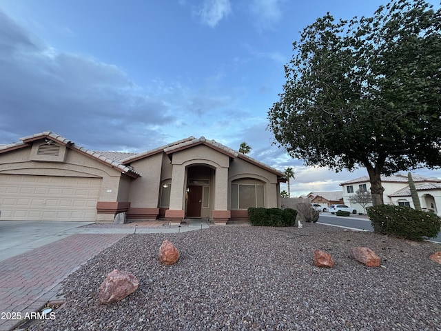 view of front facade with stucco siding, a garage, driveway, and a tile roof