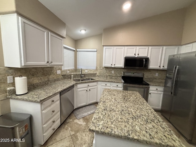 kitchen featuring a sink, white cabinetry, stainless steel appliances, light stone countertops, and vaulted ceiling