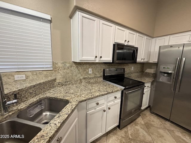 kitchen with tasteful backsplash, light stone countertops, white cabinets, stainless steel appliances, and a sink