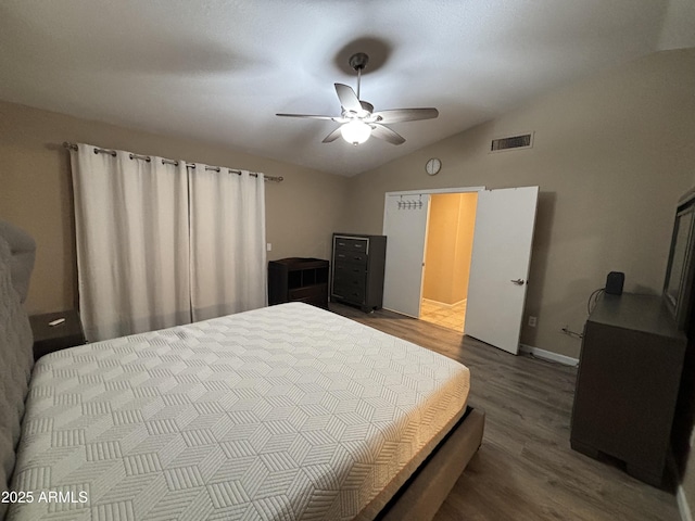 bedroom featuring baseboards, visible vents, dark wood finished floors, ceiling fan, and vaulted ceiling