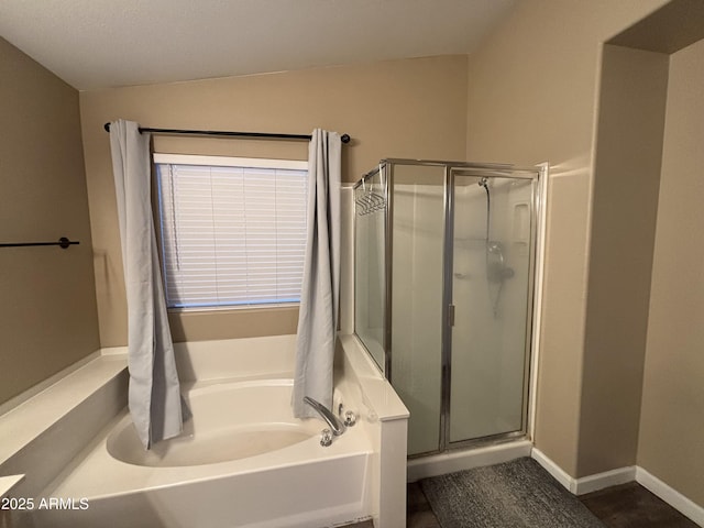 bathroom featuring a bath, a stall shower, and baseboards