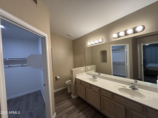 full bath with visible vents, toilet, wood finished floors, and a sink