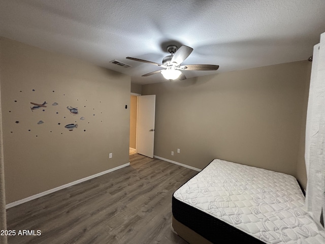 unfurnished bedroom featuring a textured ceiling, a ceiling fan, baseboards, and wood finished floors