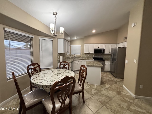 dining space featuring a notable chandelier, baseboards, and vaulted ceiling