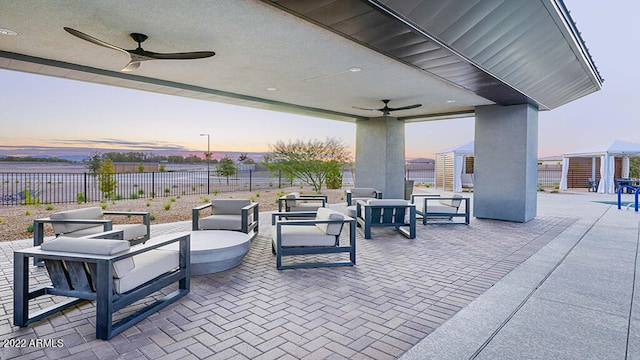 patio terrace at dusk featuring ceiling fan and an outdoor hangout area