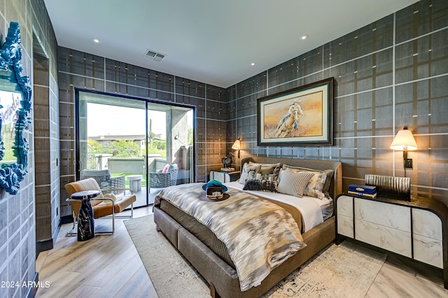 bedroom featuring wood-type flooring, tile walls, and access to outside