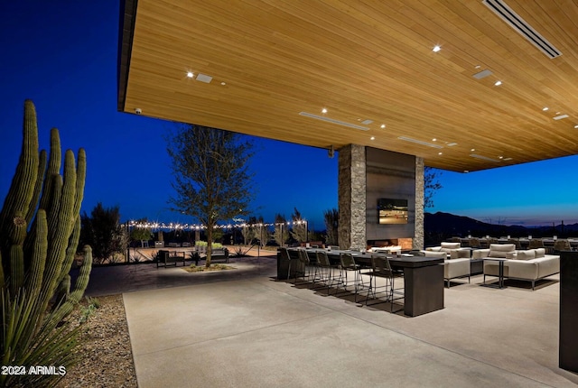 patio terrace at dusk featuring an outdoor living space with a fireplace