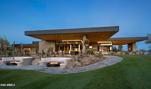 rear view of property featuring an outdoor fire pit, a patio, and a lawn