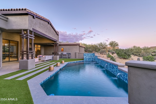 pool at dusk featuring an outdoor living space, a patio area, and pool water feature