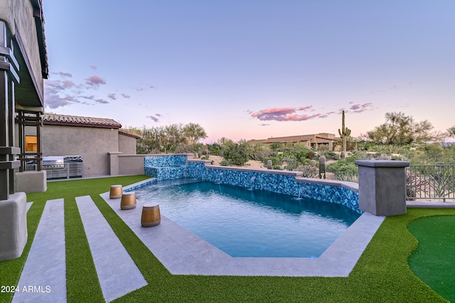 pool at dusk with a yard and pool water feature