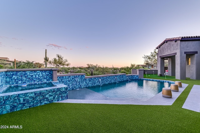 pool at dusk with a yard, a patio area, and pool water feature