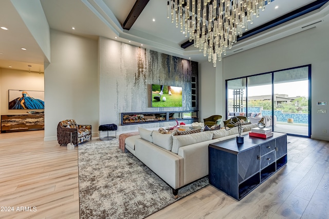 living room featuring a towering ceiling, an inviting chandelier, and hardwood / wood-style flooring