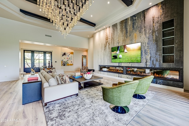 living room featuring a high ceiling, a fireplace, a tray ceiling, and wood-type flooring