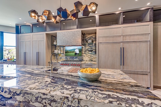 kitchen featuring dark stone countertops, light brown cabinetry, and decorative light fixtures