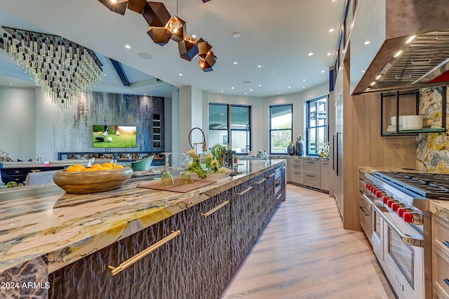 kitchen with light wood-type flooring, high end stainless steel range oven, hanging light fixtures, island exhaust hood, and wood counters