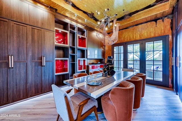 dining area featuring french doors, light wood-type flooring, and a chandelier