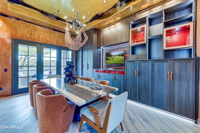 dining space with french doors, light hardwood / wood-style floors, an inviting chandelier, and wooden walls