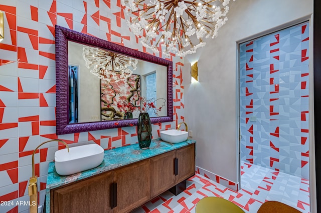 bathroom with an inviting chandelier, vanity, and tile walls