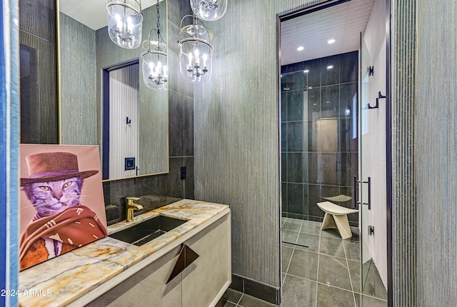 bathroom featuring an inviting chandelier, vanity, a tile shower, and tile patterned floors