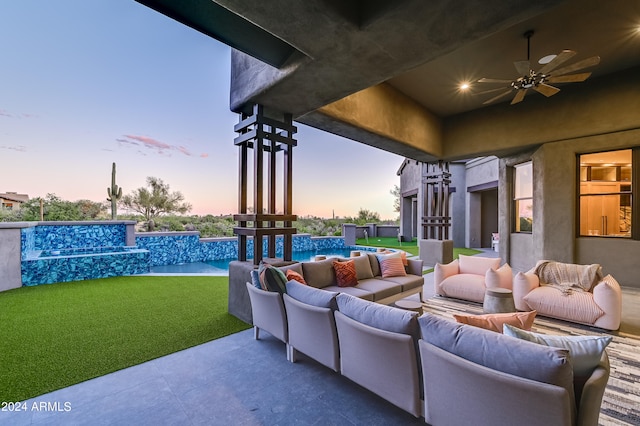 patio terrace at dusk with an outdoor hangout area, a yard, and ceiling fan