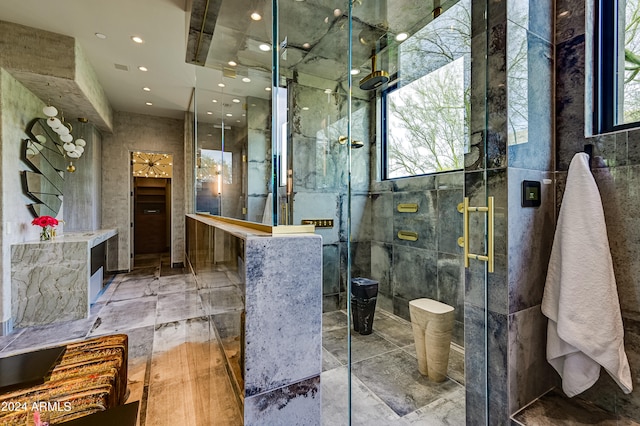 bathroom with a shower with shower door, a wealth of natural light, and tile walls