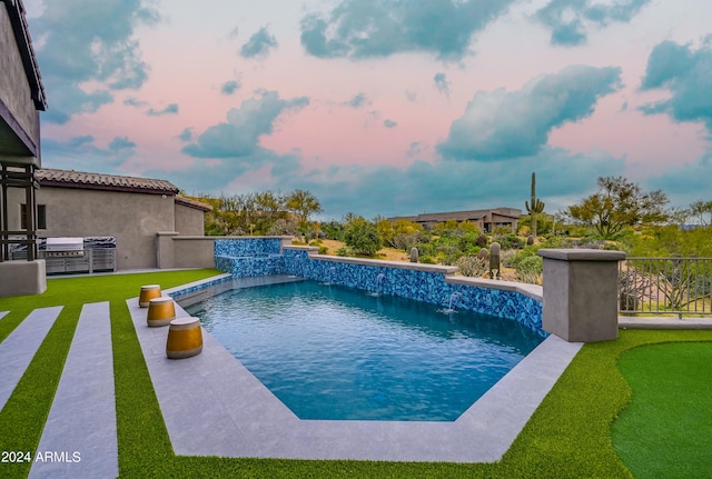 pool at dusk featuring pool water feature