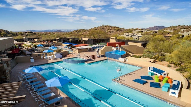 view of swimming pool with a mountain view, a patio, and a hot tub