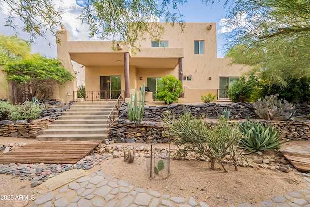 rear view of house with stairs and stucco siding
