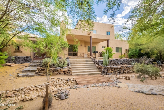 rear view of property with stairs and stucco siding