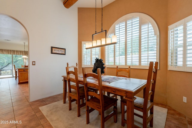 dining area featuring light tile patterned floors and a towering ceiling