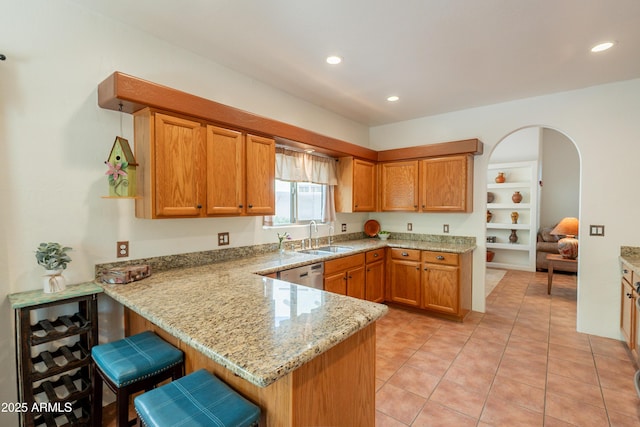 kitchen with a peninsula, recessed lighting, a sink, and light stone counters