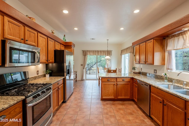 kitchen with a sink, appliances with stainless steel finishes, brown cabinets, and a peninsula
