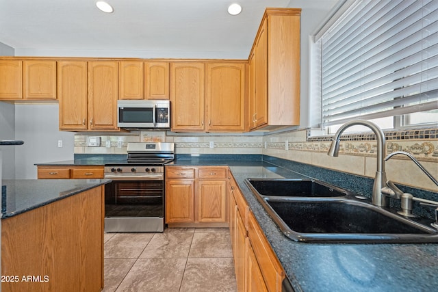 kitchen featuring light tile patterned floors, dark countertops, a sink, stainless steel appliances, and backsplash