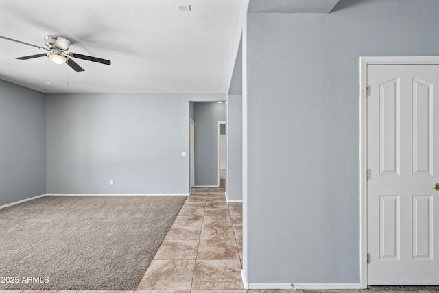 spare room featuring ceiling fan, baseboards, and light colored carpet