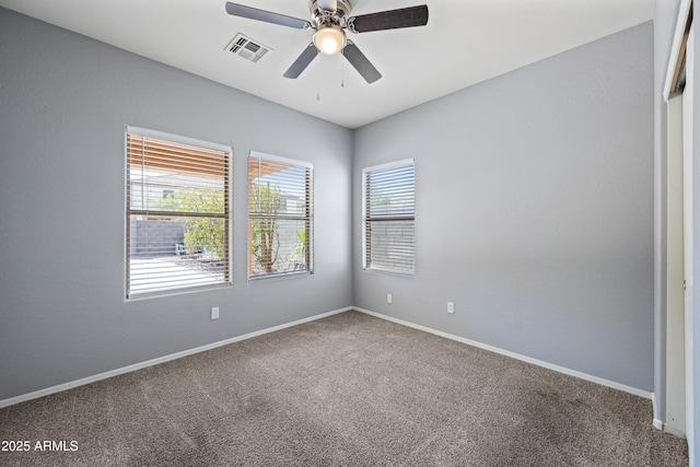 carpeted spare room with ceiling fan, visible vents, and baseboards