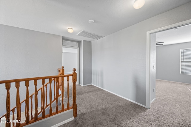 hall with an upstairs landing, carpet flooring, visible vents, and baseboards