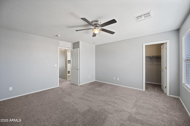 unfurnished bedroom with baseboards, visible vents, a spacious closet, and carpet flooring