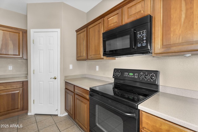 kitchen with light tile patterned floors, brown cabinets, black appliances, and light countertops