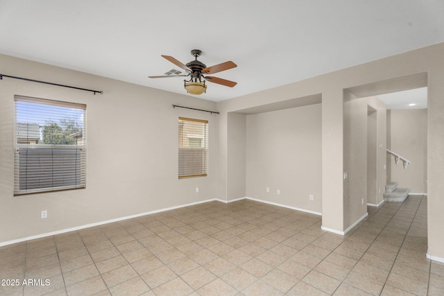 unfurnished room with light tile patterned floors, baseboards, a ceiling fan, and stairs