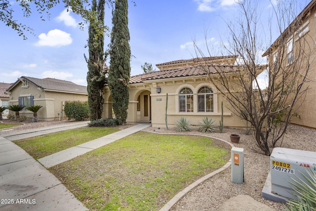 mediterranean / spanish home with stucco siding, a tiled roof, and a front lawn