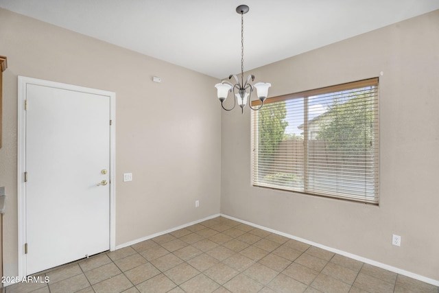 spare room featuring baseboards and a chandelier