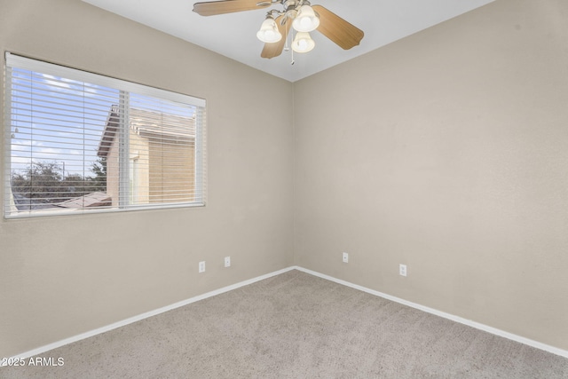 carpeted spare room featuring ceiling fan and baseboards